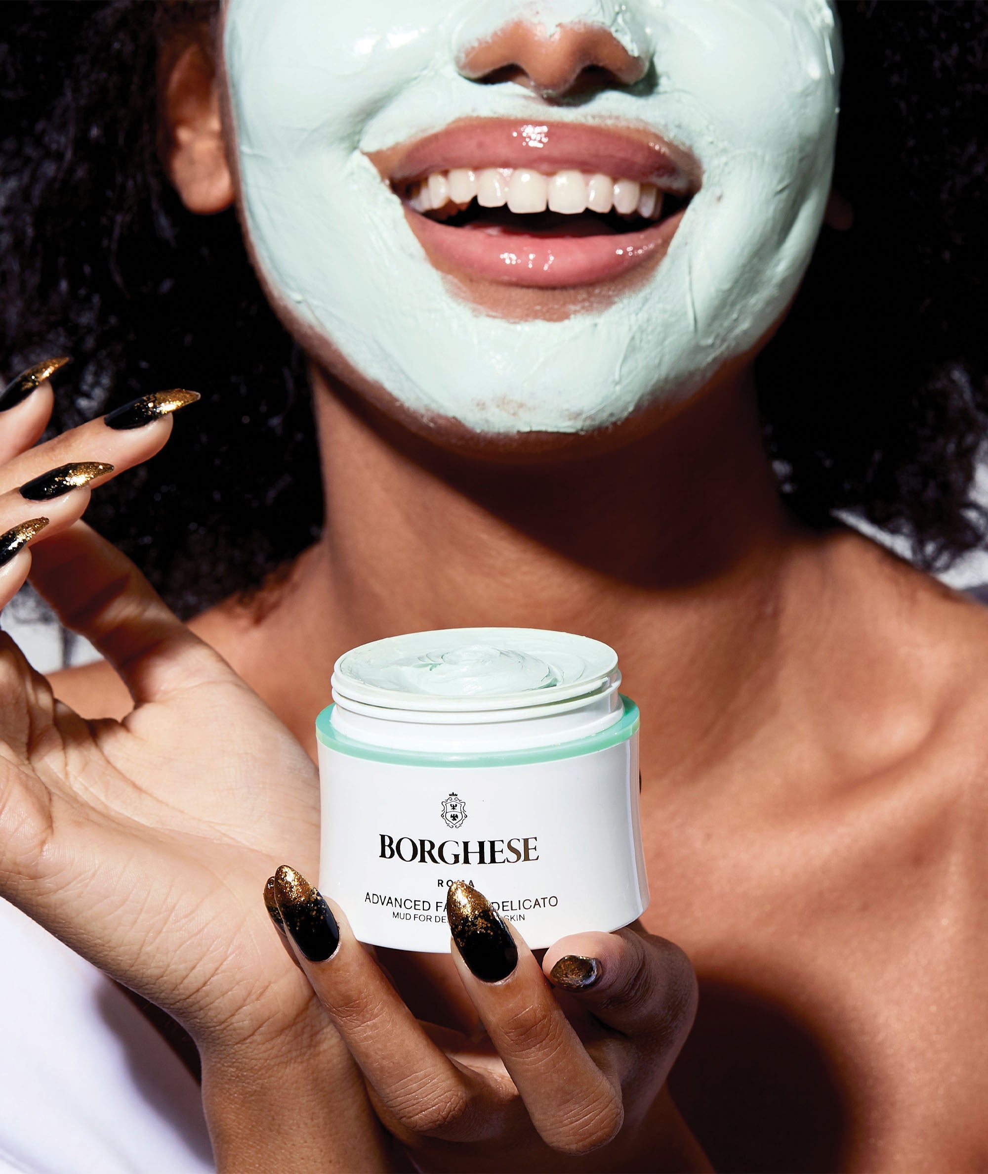 Model using our travel size Advanced Fango Delicato Mud Mask on her face and holding jar