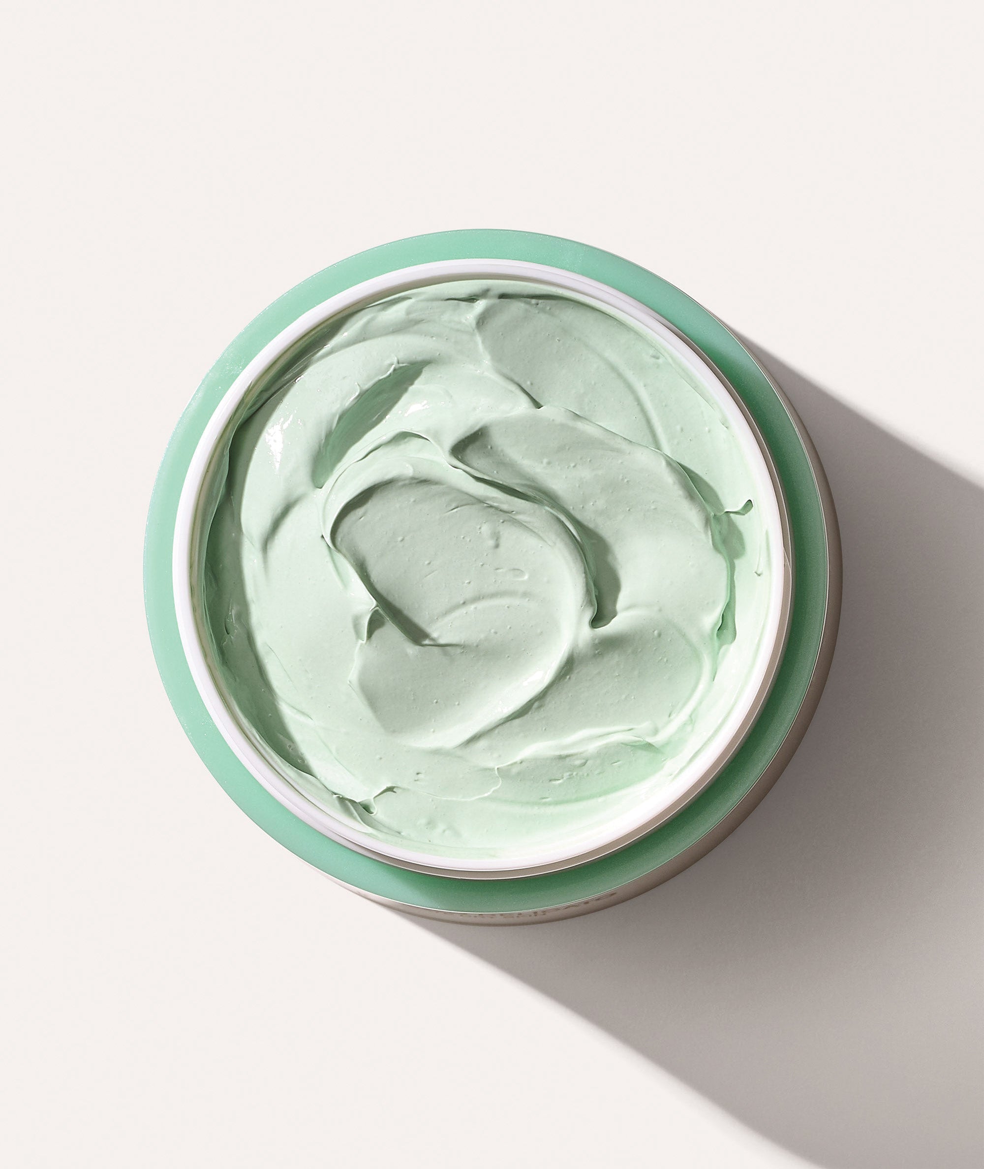 Aerial view of Fango Delicato jar open showing the mint green color and texture of the mud mask
