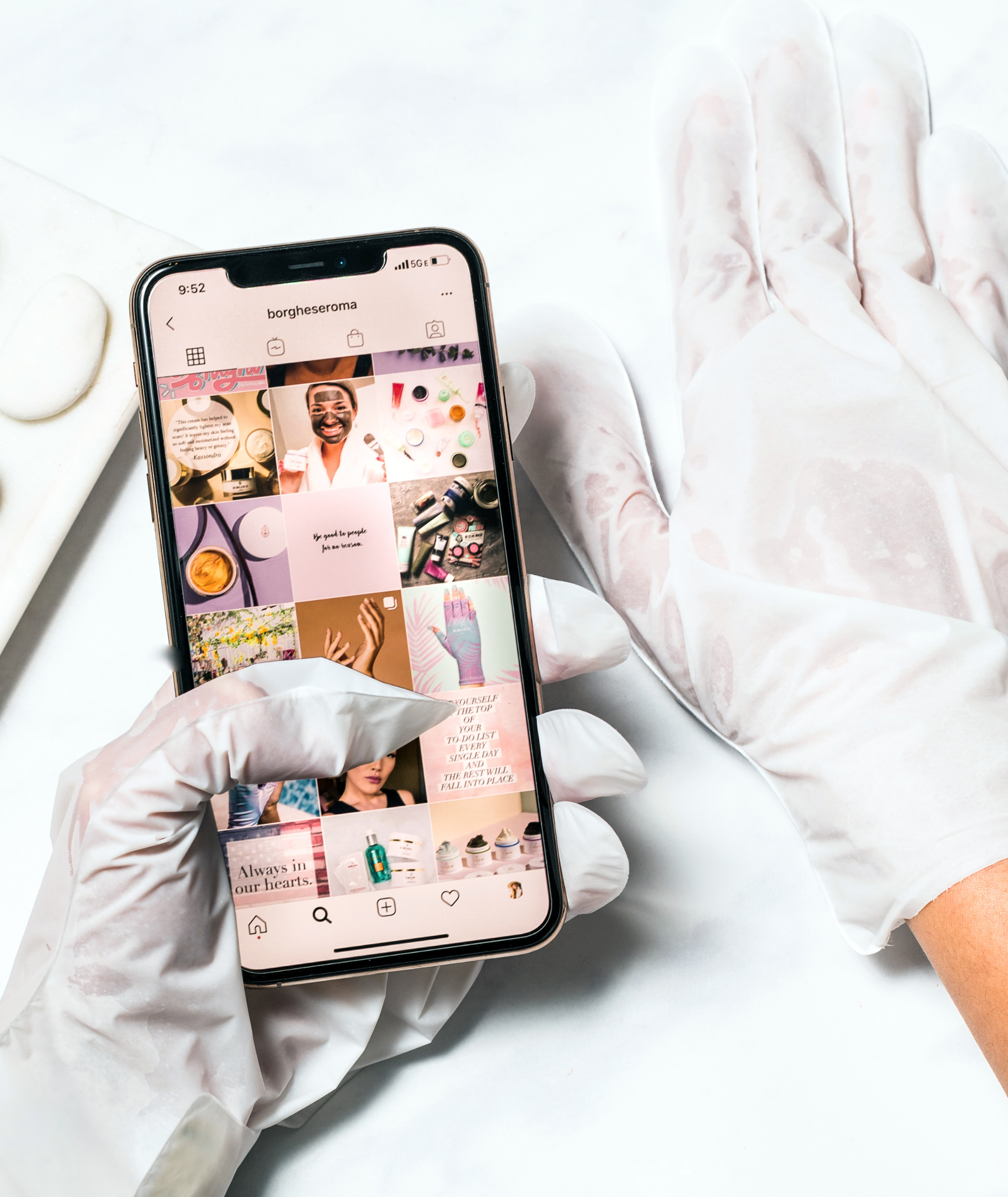Model's hand with Deep Hydration Hand Sheet Masks on while using phone to show the touch screen feature