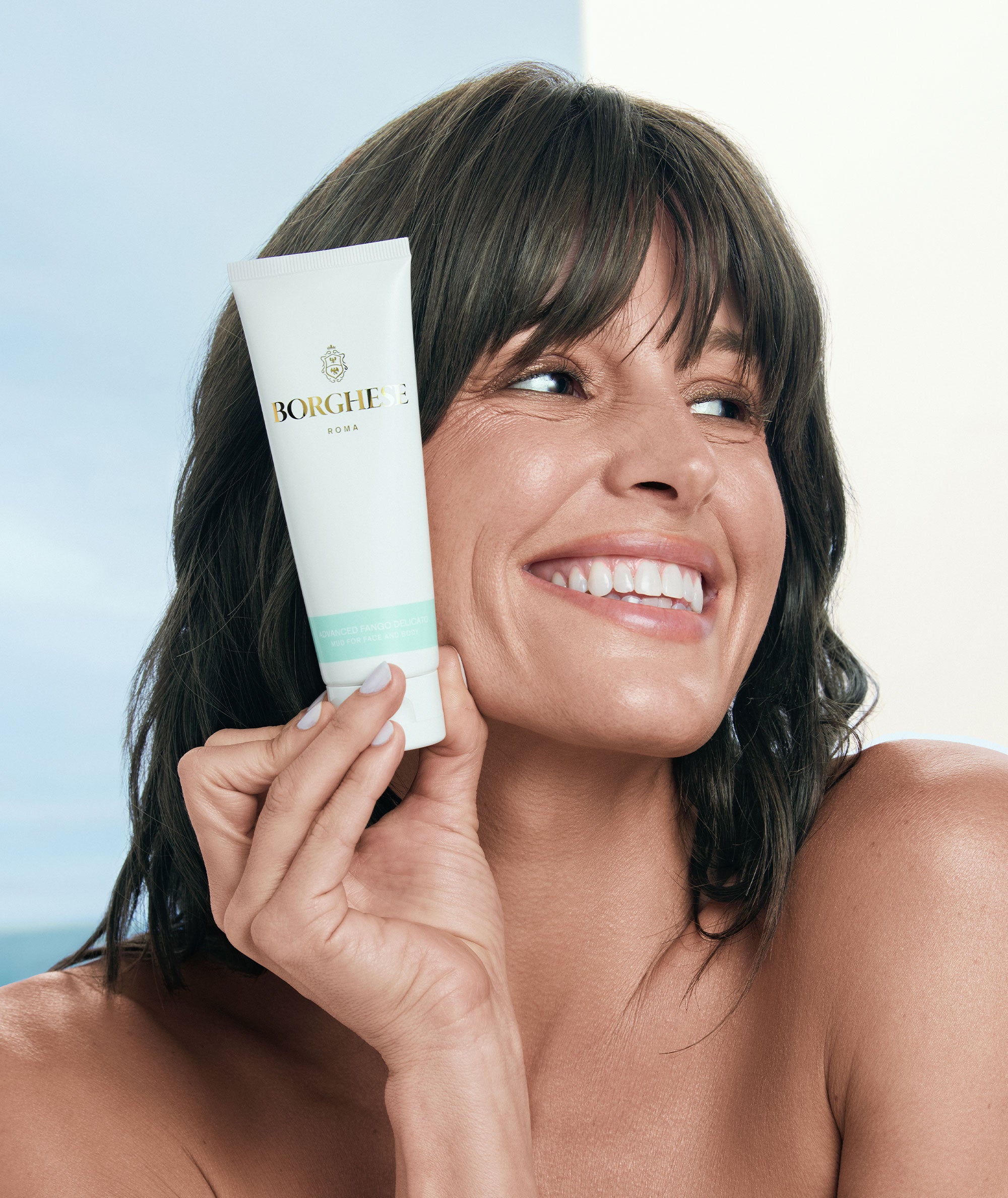 A lifestyle shot of a model showing our travel size Advanced Fango Delicato tube