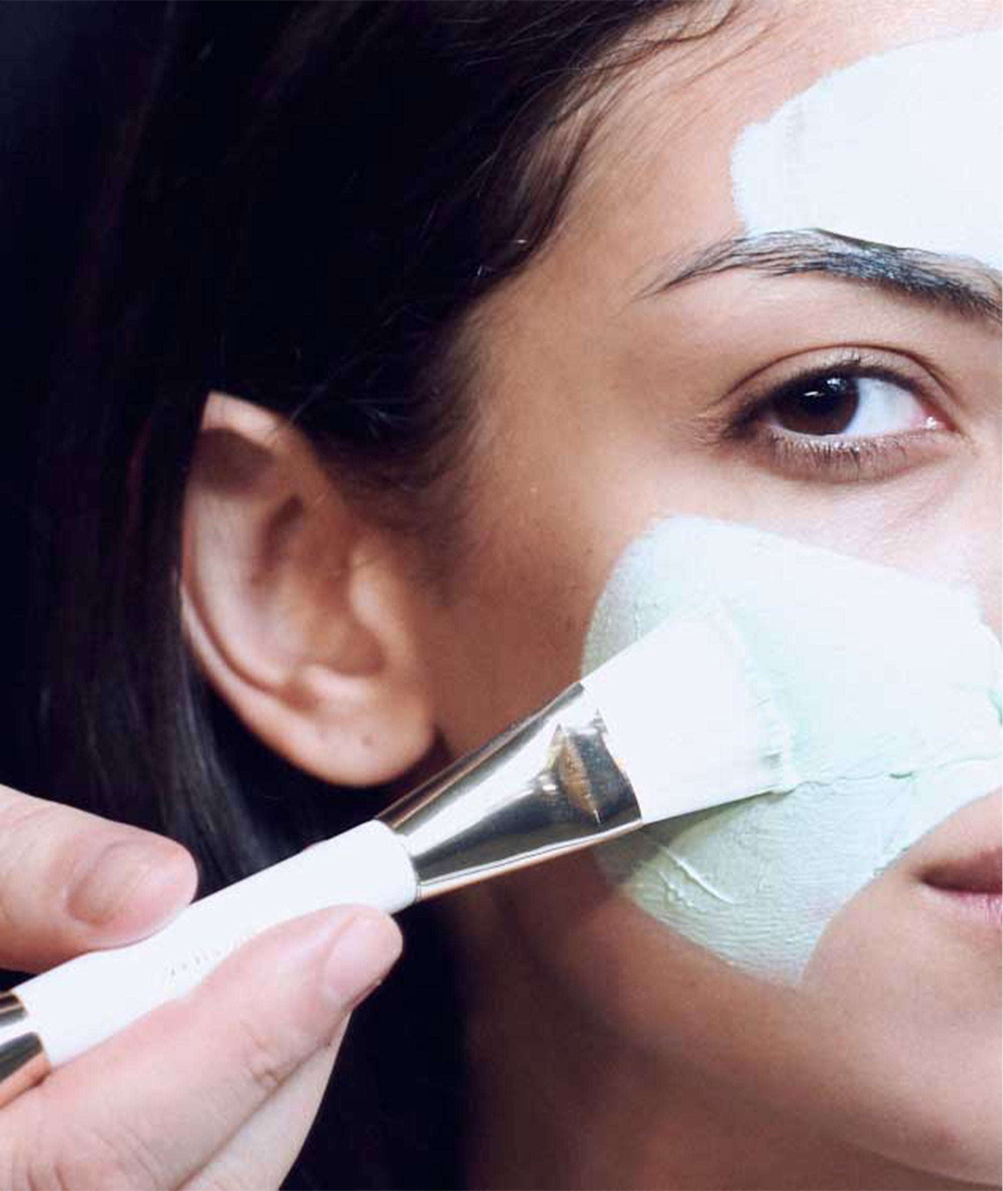 Model using the brush end of the mask applicator with our Advanced Fango Delicato Mud Mask.