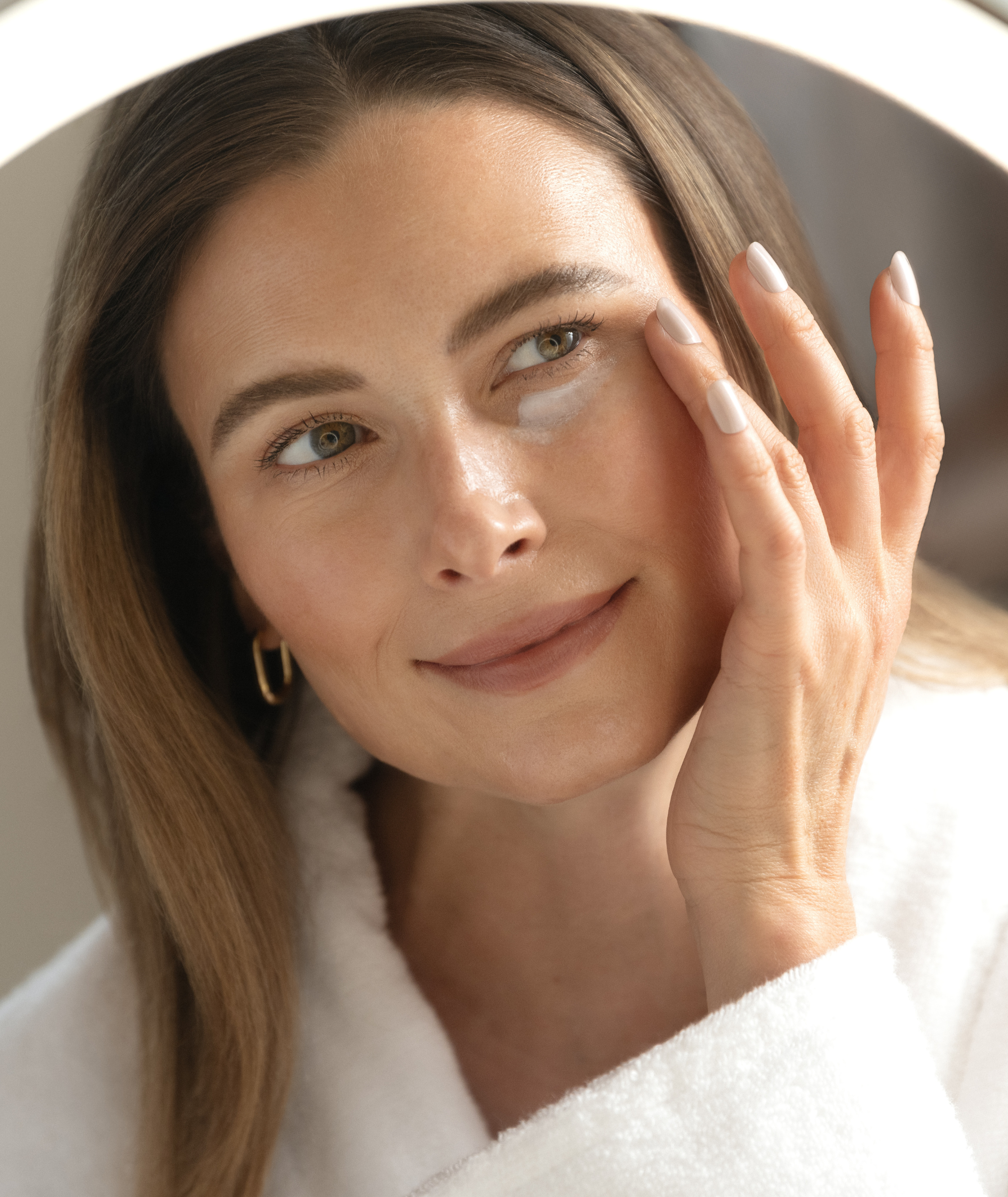 Model delicately applying Fluido Protettivo under her eyes.