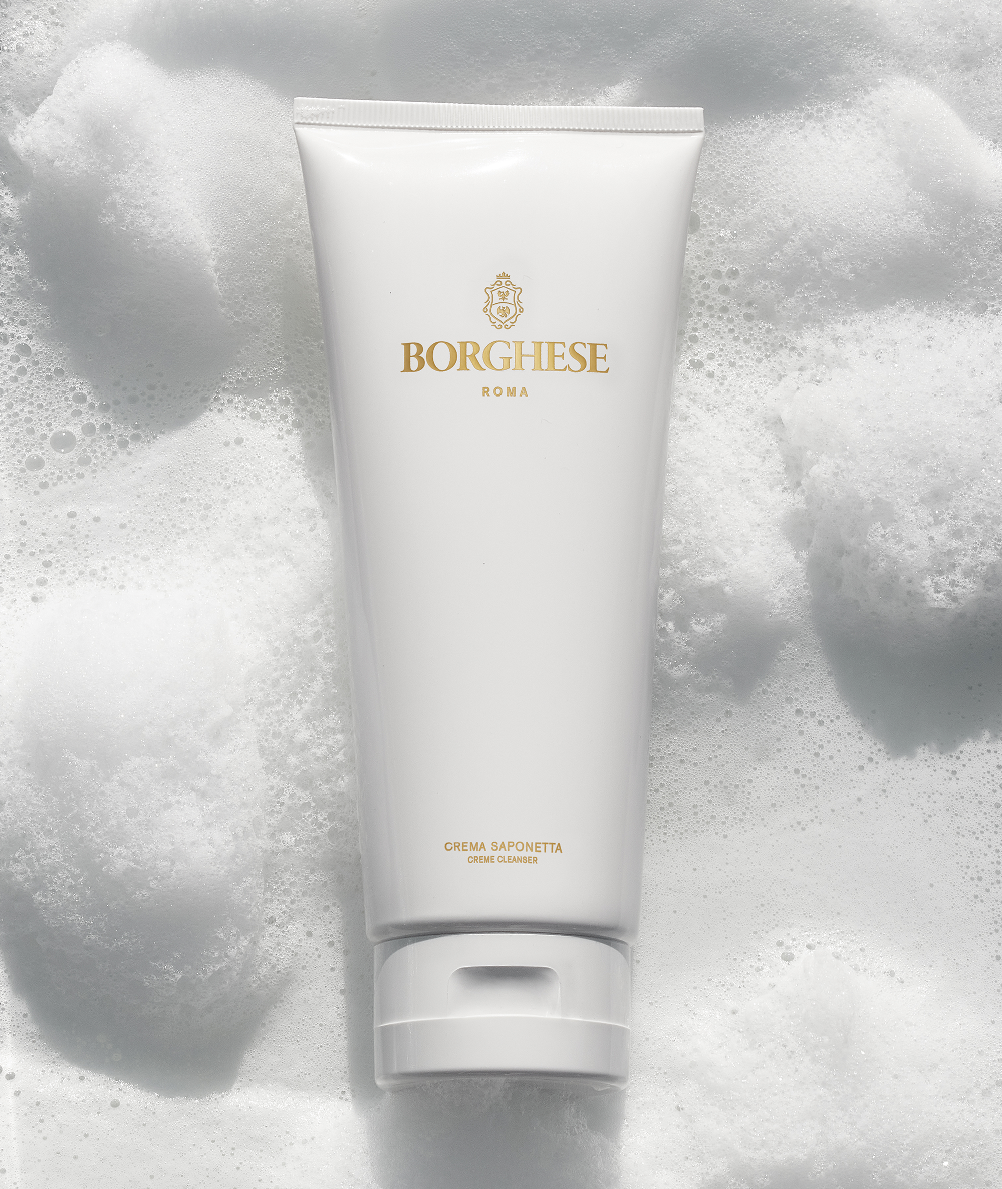 Lifestlye image of Crema Saponetta Cleanser tube on top of a bubbly background, emphasizing its foaming property