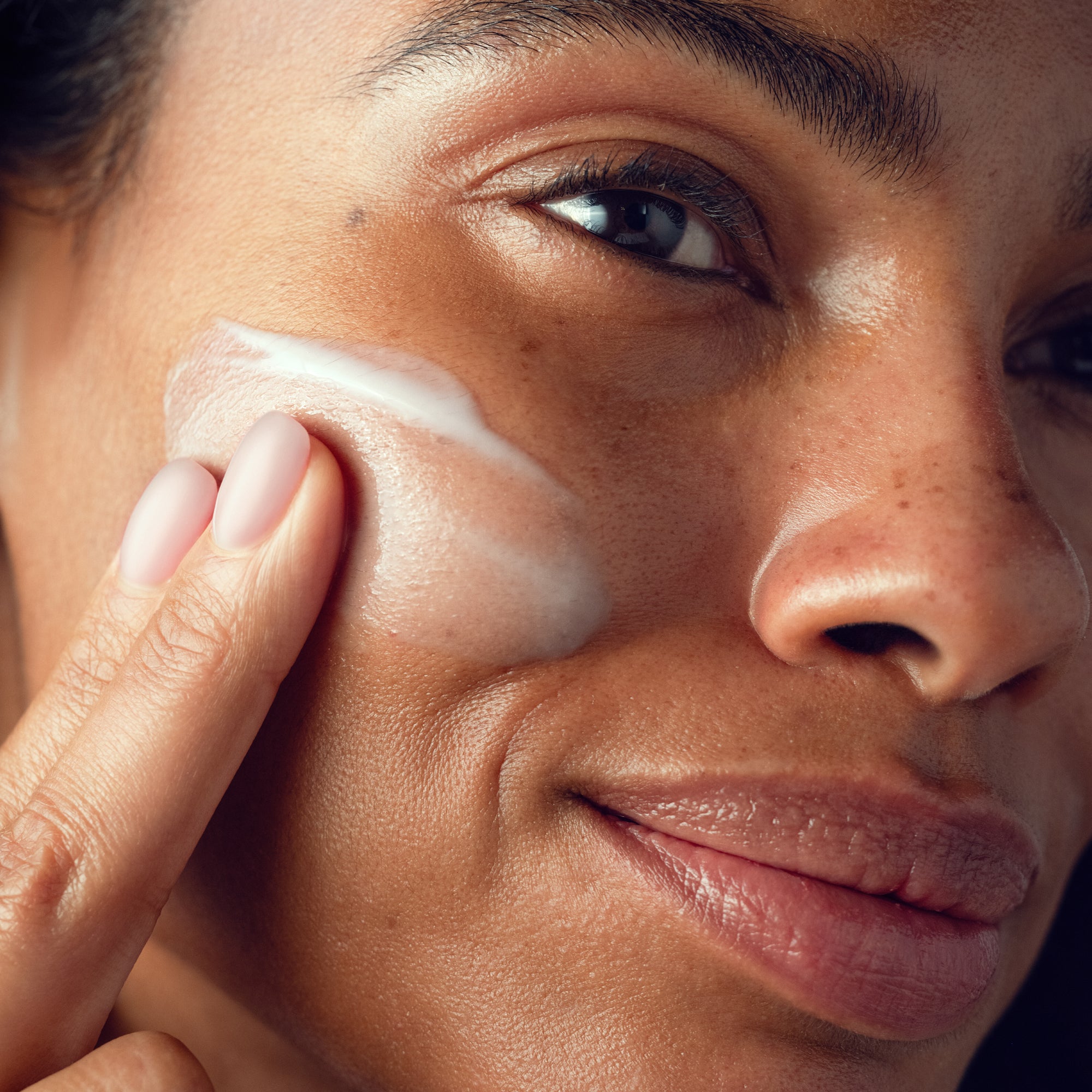 A lifestyle image of a model using the Overnight Resurfacing Mask on her face.