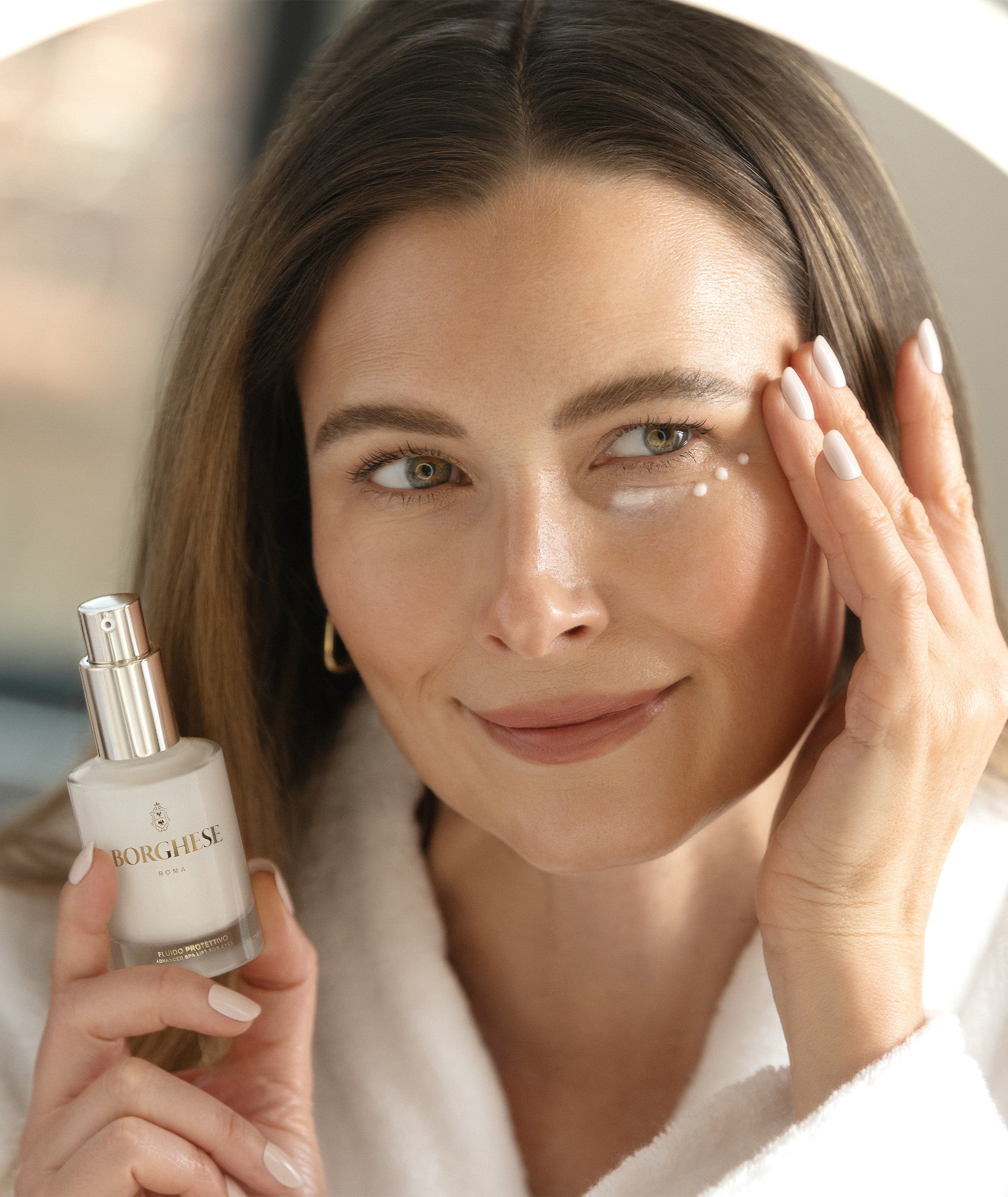 Model delicately applying Fluido Protettivo under her eyes